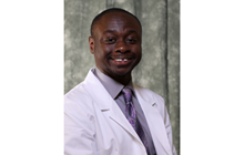 KCU student doctor Reggie Boateng smiles in his white coat. 